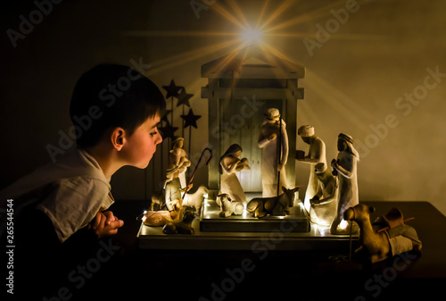 Young boy leaning in looking closely at a ceramic nativity scene. photo