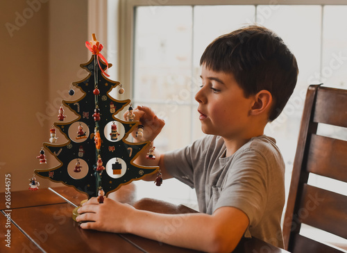 Young boy looking closely at wooden table top Christmas tree.