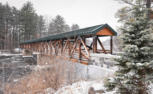 Covered wooden bridge across a river on a snowy day. photo