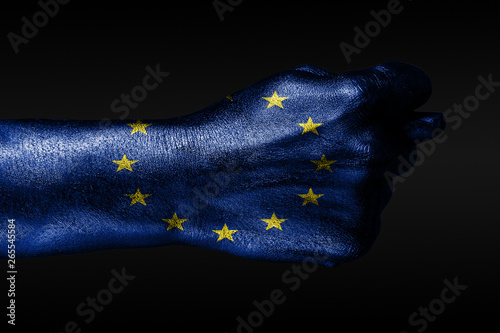 A hand with a painted EU flag shows a fig, a sign of aggression, disagreement, a dispute on a dark background.