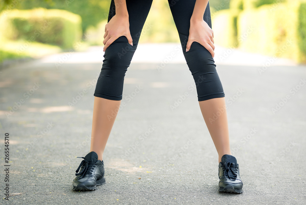 Female legs with close-up hands in them, a symbol of fatigue after running or sports activities Female legs with close-up hands in them, a symbol of fatigue after running or sports activities