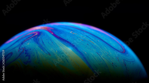 Psychedelic abstract planet-like soap bubble, light refraction on a soap bubble, colors in soap bubble.