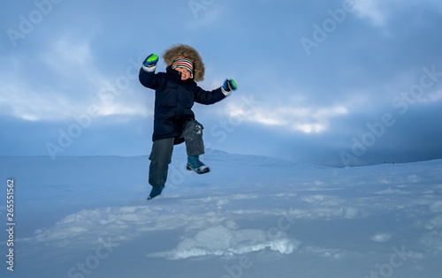 Happy little boy jumping in the snow