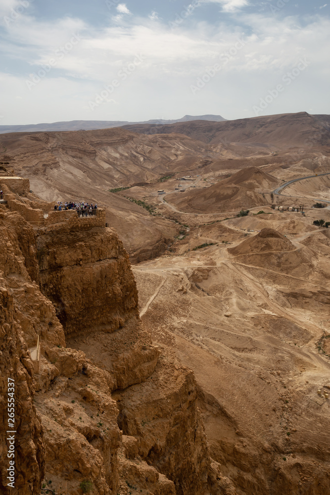Beautiful view of an ancient fortress on top of a mountain during a cloudy and sunny day. Taken in Masada National Park, Israel.