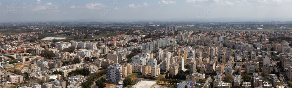 Aerial panoramic view of a residential neighborhood in a city during a cloudy and sunny day. Taken in Netanya, Center District, Israel.
