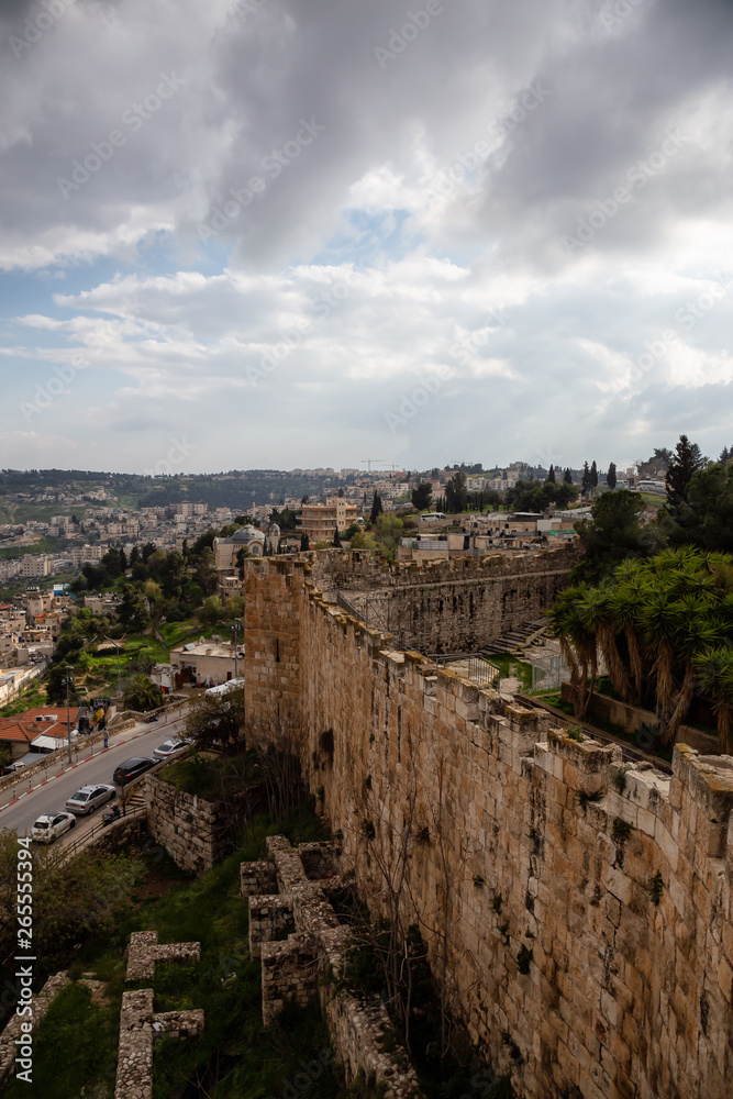 Beautiful view of the Walls of Jerusalem surrounding the Old City with the cityscape in the background during a cloudy day. Taken near the Jerusalem, Israel.