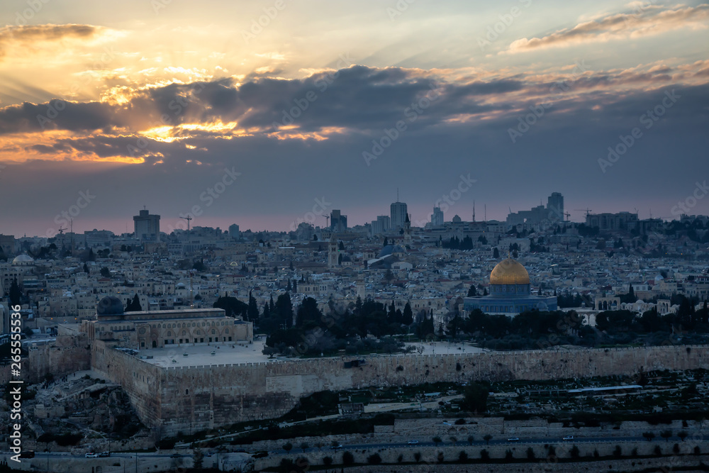 Beautiful aerial view of the Old City and Dome of the Rock during a dramatic colorful sunset with sunrays. Taken in Jerusalem, Capital of Israel.