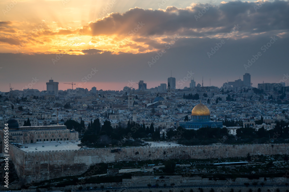 Beautiful aerial view of the Old City and Dome of the Rock during a dramatic colorful sunset with sunrays. Taken in Jerusalem, Capital of Israel.