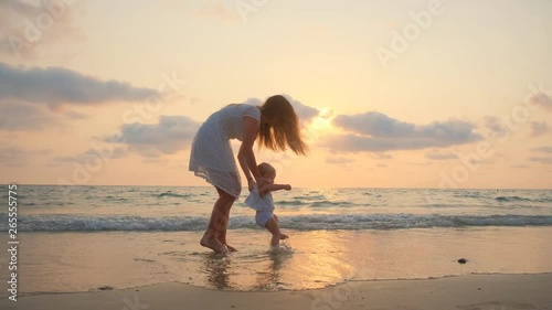 YounYoung Beautiful Woman Walks With Her Little baby On The Seashore At Sunsetg Beautiful Woman Walks With Her Little baby On The Seashore At Sunset. 4k