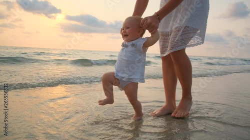 YounYoung Beautiful Woman Walks With Her Little baby On The Seashore At Sunsetg Beautiful Woman Walks With Her Little baby On The Seashore At Sunset. 4k