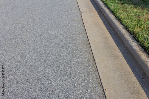 Formed concrete curb with green grass, asphalt copy space, horizontal aspect