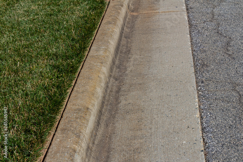 Nicely edged green grass alongside a formed concrete curb, horizontal aspect