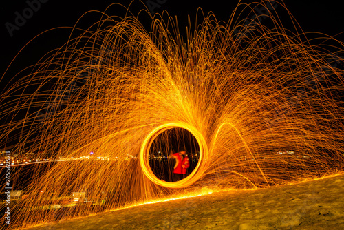 Large round burning fireworks sparkle from the burning steel wool. The city lights at night.