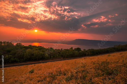 Wallpaper, natural scenery (reservoirs, mountains, rivers) and bright light, colorful sky, beautiful evening, blurred through the grass, atmosphere surrounded by trees © bangprik