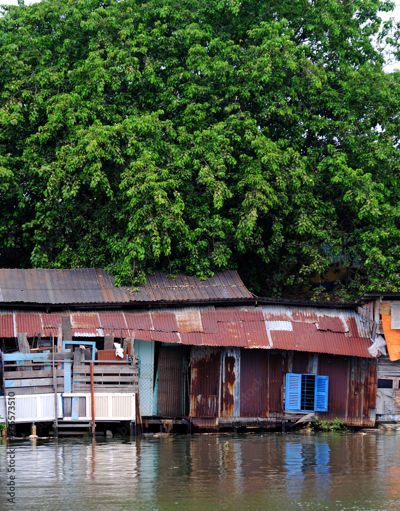riverside old downgrade house from corrugated metal sheet under big tree
