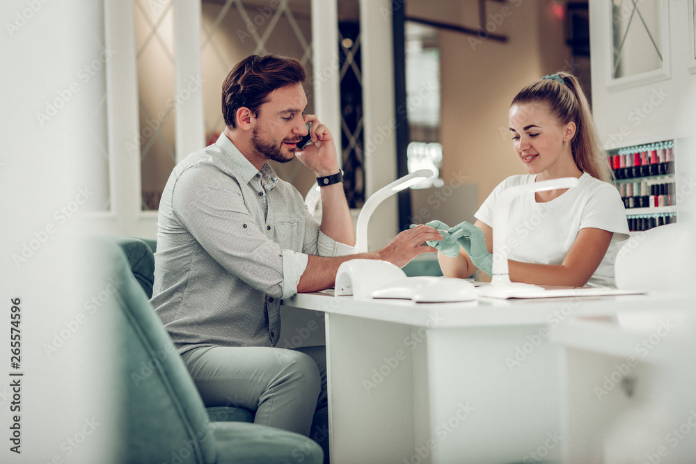 Elegant good-looking dark-haired man with beard visiting nails salon Elegant good-looking dark-haired man with beard visiting nails salon
