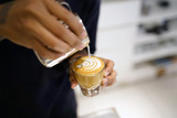 Barista making coffee with latte art, Created by pouring steamed milk into a shot of espresso and resulting in a pattern or design on the surface of the latte.