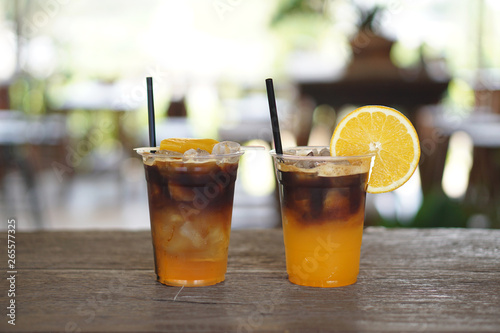 Iced coffee shakerato - Plastic glass of espresso shot mixed with craft soda and orange juice on blurred background.