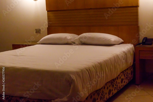Double bed with two pillows in bedroom in soft lights