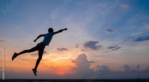 Happy man jumping for joy on the peak of the mountain  cliff at sunset. Success  winner  happiness