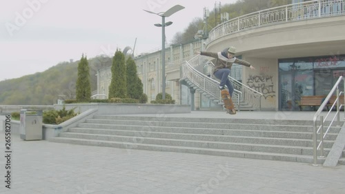 Young skater jumping over stairs performing good technique of skateboard ollie trick outdoors in city street. Active teenager practicing skateboard jump rolling on skate, extreme sport lifestyle. photo