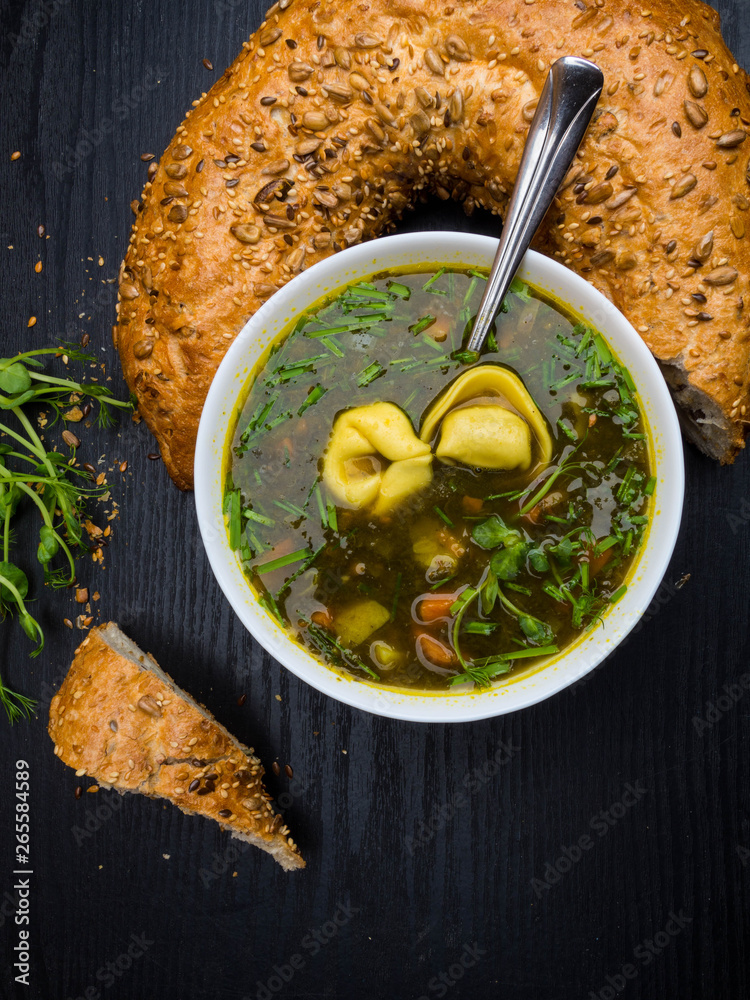 Hot sorrel and spinach soup with bread and dumplings on wooden background.