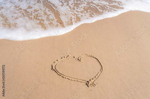 Heart drawing on the sea wet sand