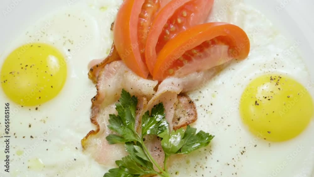 English breakfast. Close-up shot of three fried eggs and bacon serving on a white plate. Slow motion. HD English breakfast. Close-up shot of three fried eggs and bacon serving on a white plate. Slow motion. HD