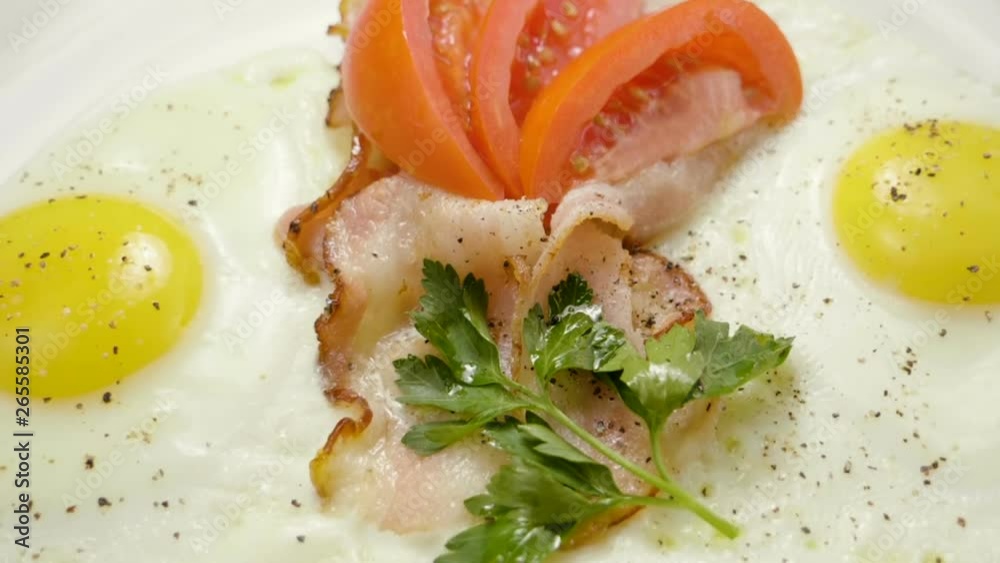 English breakfast. Close-up shot of three fried eggs and bacon serving on a white plate. Slow motion. HD