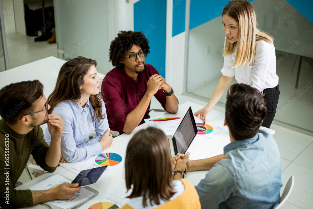 Pretty female team leader talking with mixed race group of people in the office Pretty female team leader talking with mixed race group of people in the office
