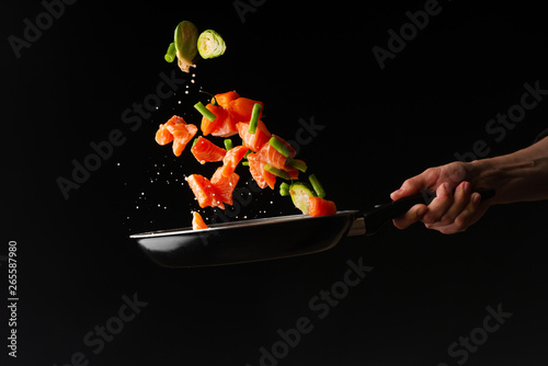 Fototapeta Naklejka Na Ścianę i Meble -  Sea food, cooking salmon with vegetables, on a dark background, horizontal photo, healthy and healthy food, freezing in the air