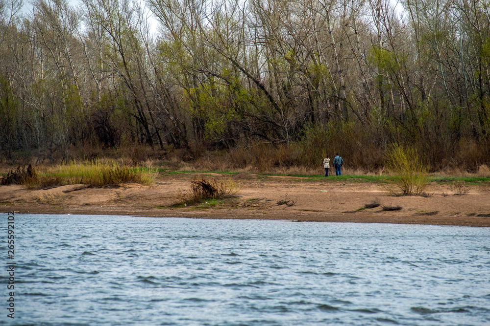 an elderly couple in love walks in windy weather on the other side of the Ural river an elderly couple in love walks in windy weather on the other side of the Ural river