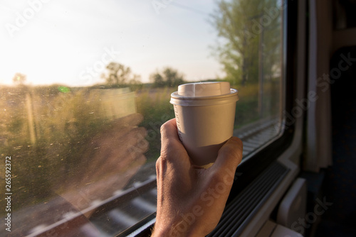 Hand holding coffe cup on train