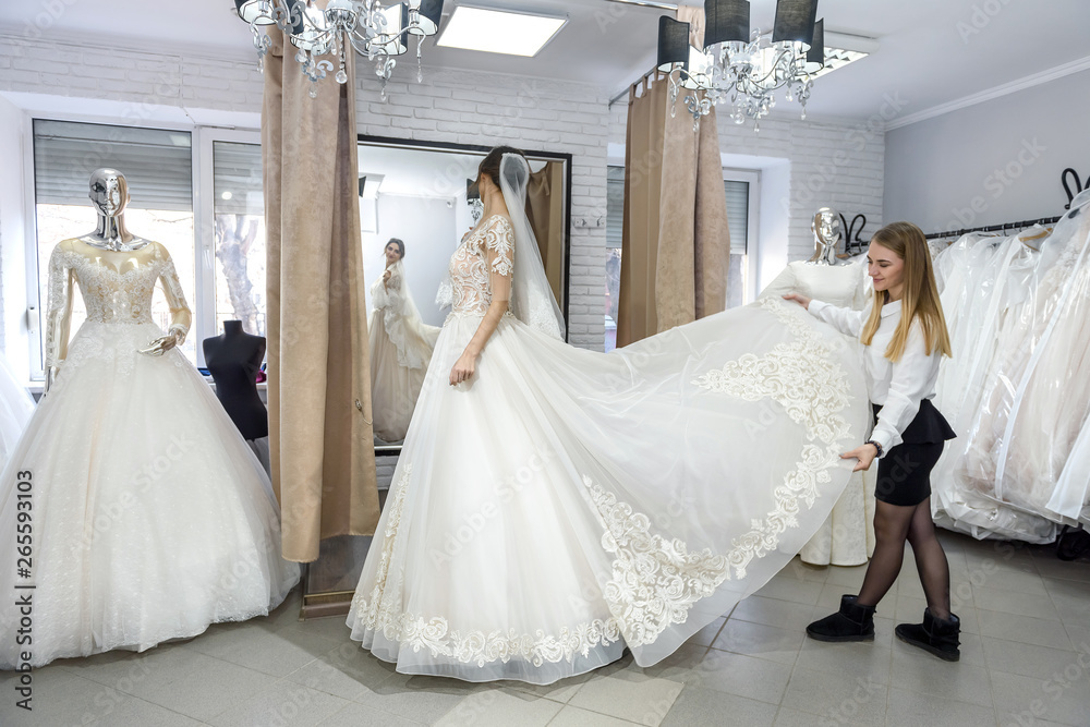 Blonde woman helping bride in wedding shop Blonde woman helping bride in wedding shop