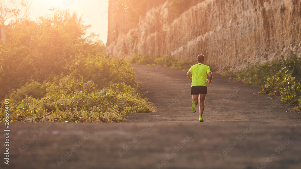 Obraz premium Man jogging on a downhill / uphill in suburb mountain road.