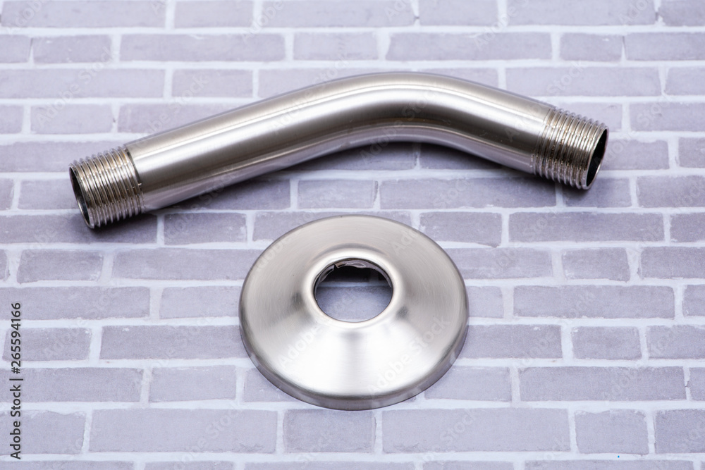 Brushed Nickel Metal Shower Arm and Flange isolated on brick wall background.