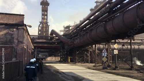 Two labouring men walk along the road on an industrial plant. Metallurgists workers are in a metallurgical complex photo