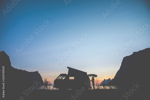 Camper van silhouette in sunset between mountains photo