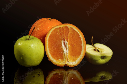 Apples and oranges fruits with drops and splashes of water on a black background