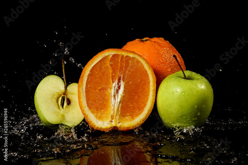 Fototapeta Naklejka Na Ścianę i Meble -  Apples and oranges fruits with drops and splashes of water on a black background