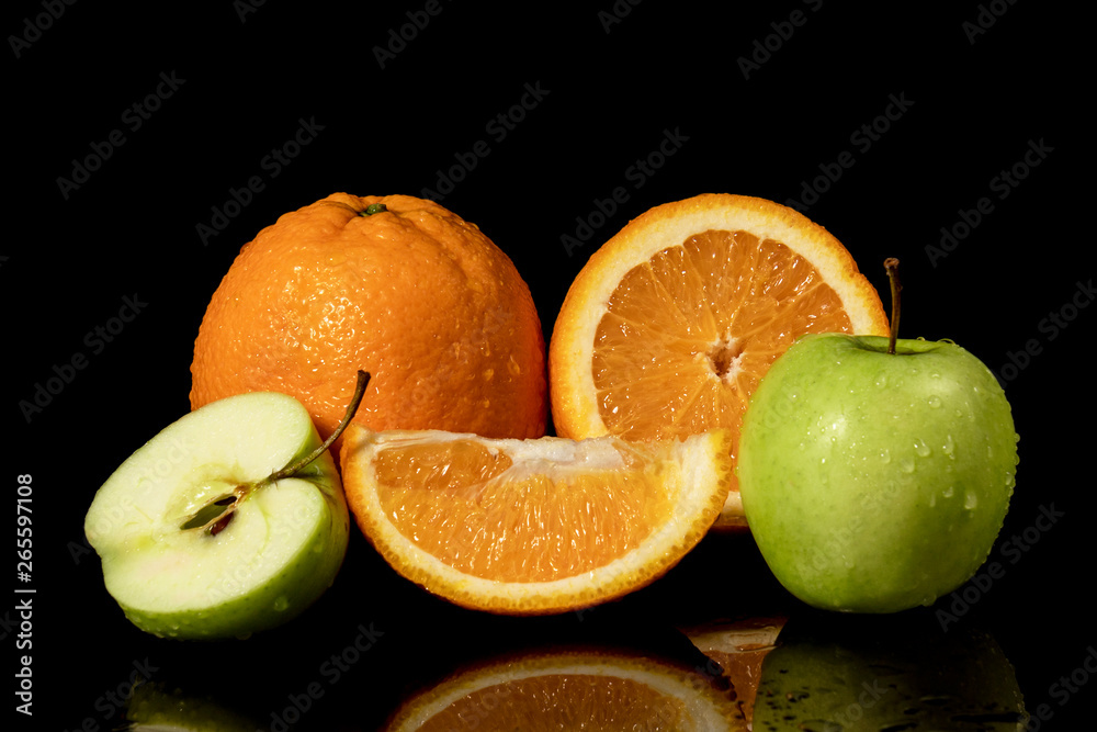 Apples and oranges fruits with drops and splashes of water on a black background Apples and oranges fruits with drops and splashes of water on a black background