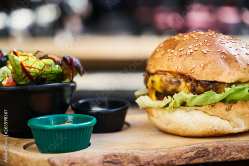 Cheeseburger with salad on the wooden table