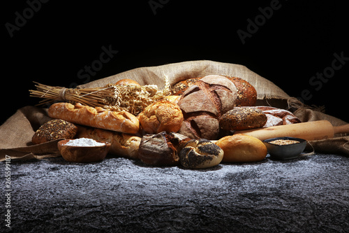 Assortment of baked bread and bread rolls on rustic grey bakery table background © beats_