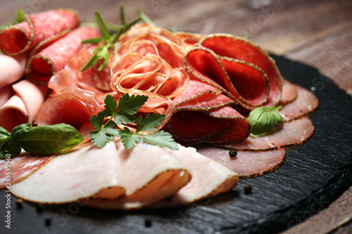 Food tray with delicious salami  pieces of sliced ham  sausages salad and vegetable. Meat platter with selection