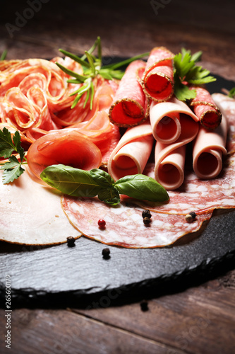 Food tray with delicious salami  pieces of sliced ham  sausages salad and vegetable. Meat platter with selection