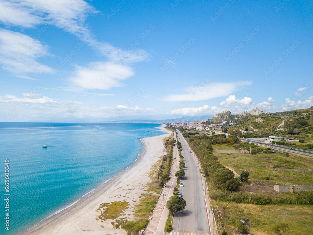 Vista aerea della città di Roccella Ionica o Jonica in Calabria, con il porto delle Grazie, il castello Carafa e la bellissima spiaggia sabbiosa con il mare Mediterraneo blu. 