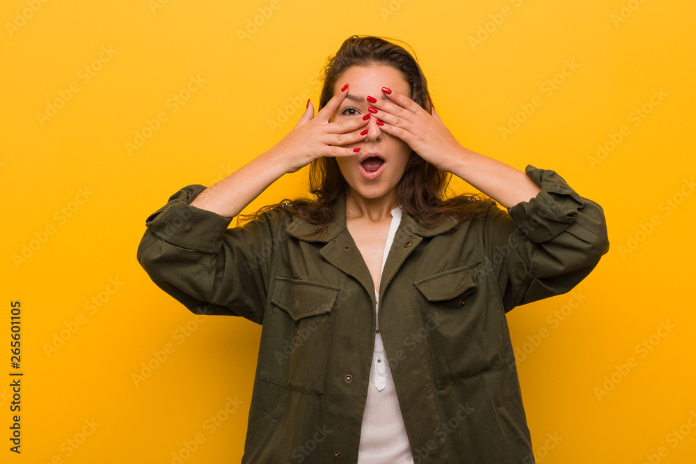 Young european woman isolated over yellow background blink through fingers frightened and nervous. Young european woman isolated over yellow background blink through fingers frightened and nervous.