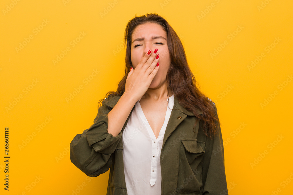 Young european woman isolated over yellow background yawning showing a tired gesture covering mouth with her hand. Young european woman isolated over yellow background yawning showing a tired gesture covering mouth with her hand.