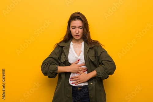 Young european woman isolated over yellow background sick, suffering from stomachache, painful disease concept. © Asier