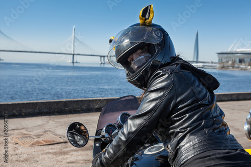 Pretty biker girl in leather jacket and black helmet with mask on